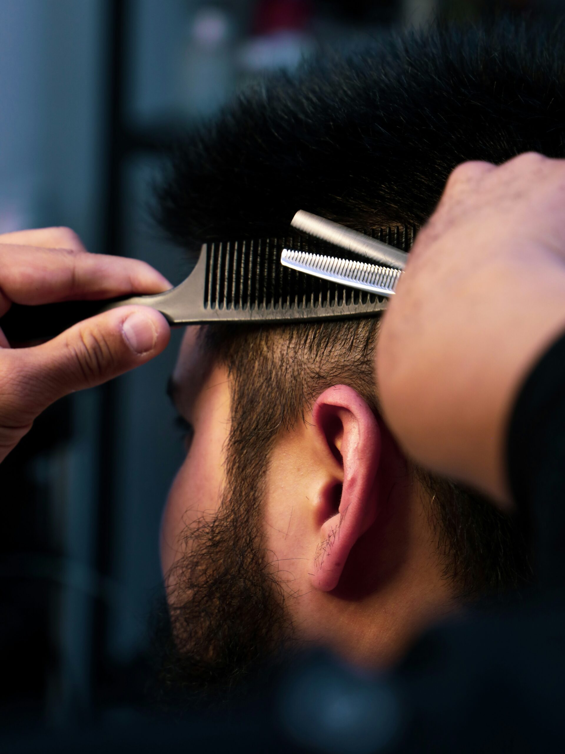 A close-up of a barber cutting a mullet for a customer, carefully shaping the sides.