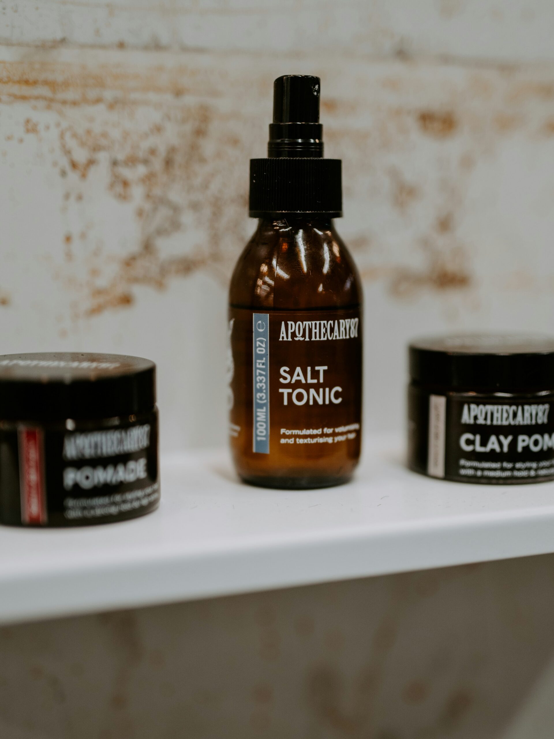 A range of hair styling products for mullet haircuts in brown containers on a white shelf.