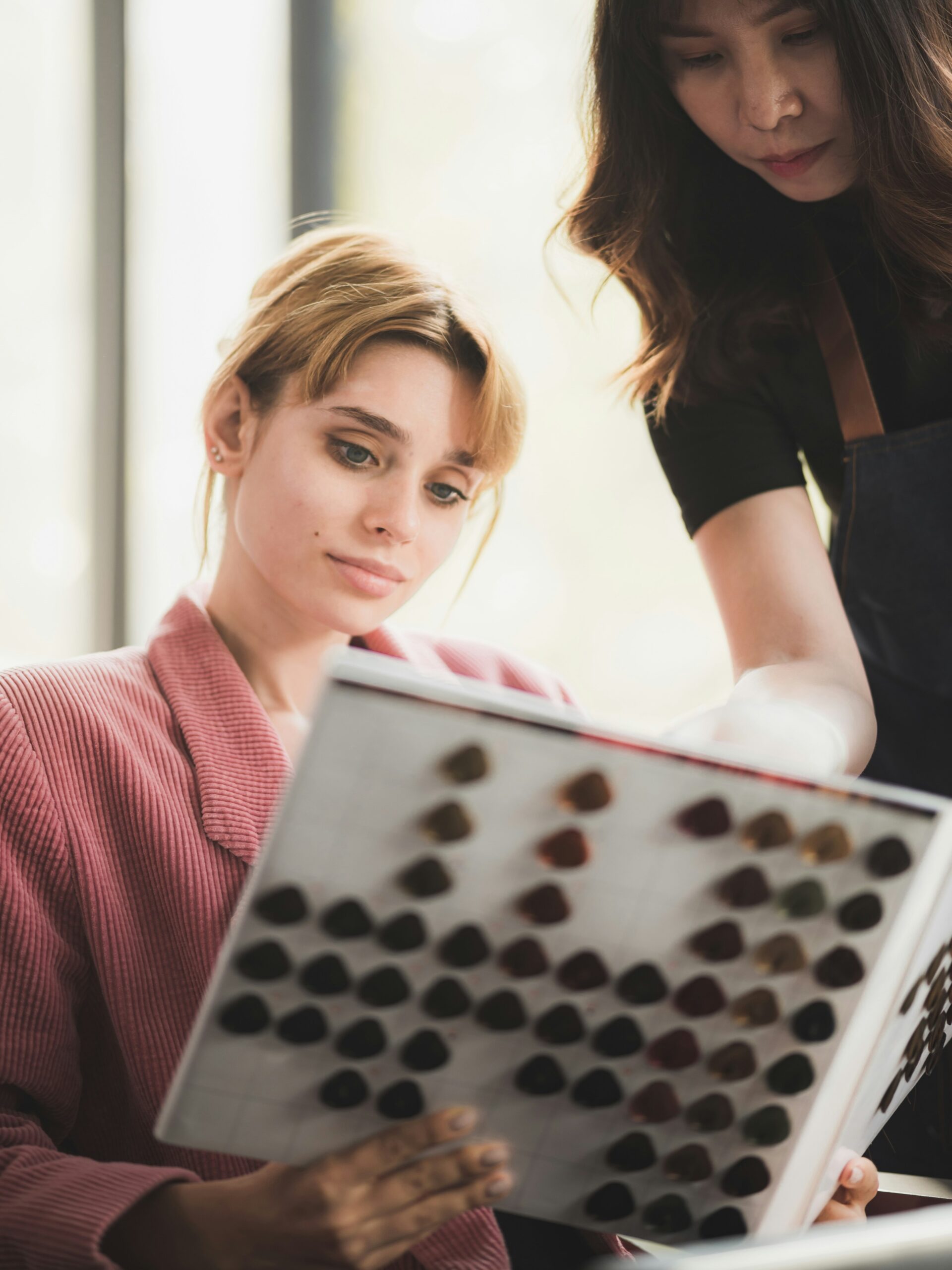 Client sits in a hairdresser’s looking at a book of colour swatches with a stylist