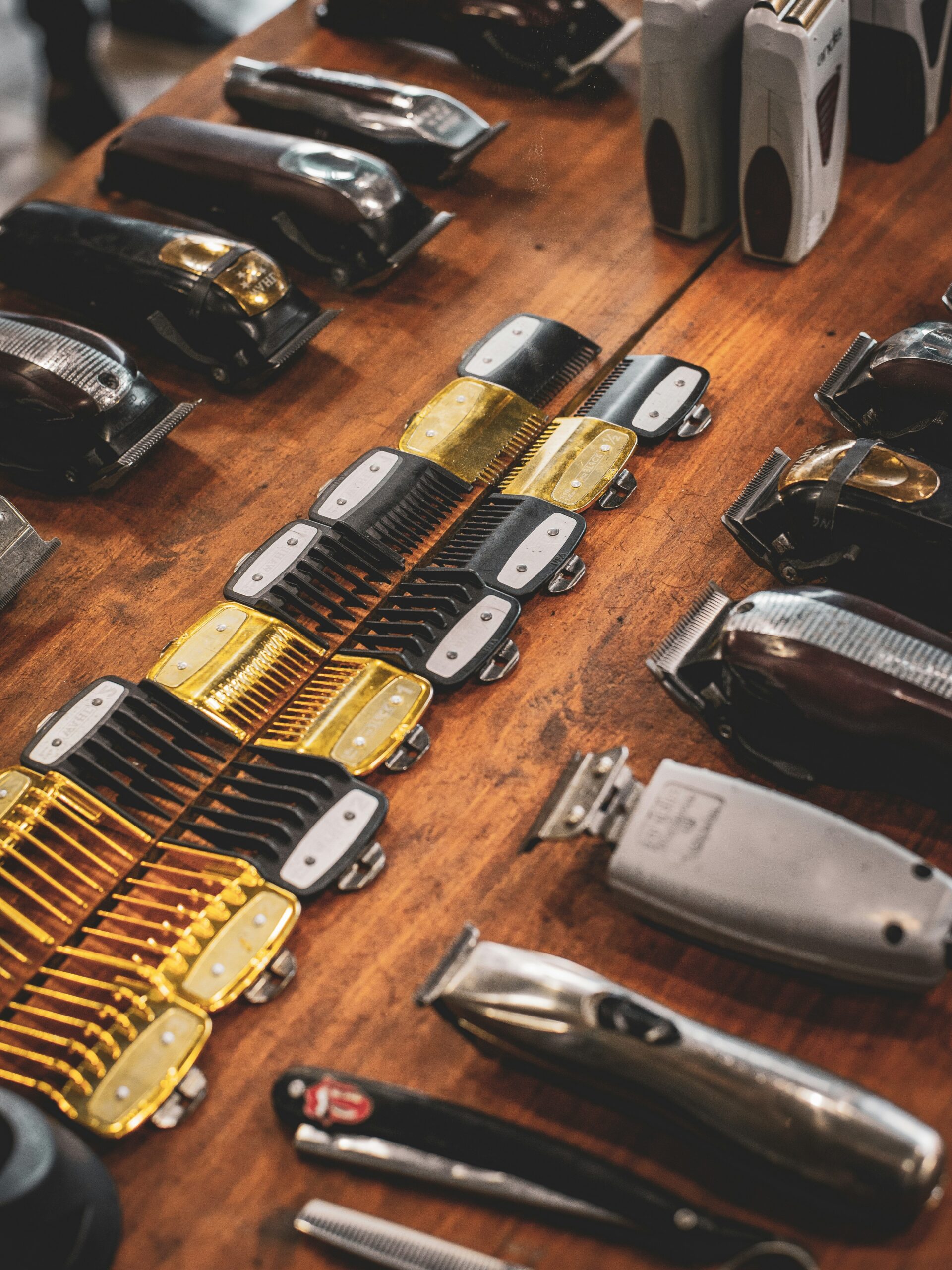Flat lay of barbers tools on a wooden shelf including clippers and guards