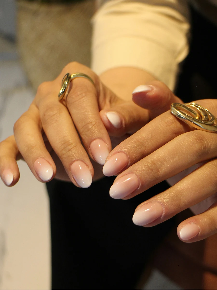 A close-up of a client’s ombre shellac manicure in classic nude shades straight after her manicure in salon