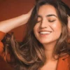 Close-up of woman smiling with her eyes closed and running her hands through her soft long brunette hair