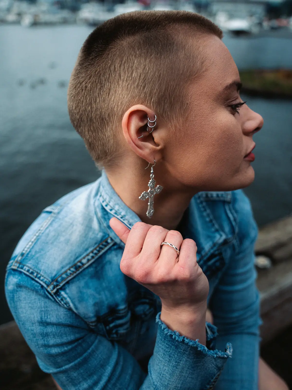 Overhead shot of a woman with forward helix, helix and lobe piercings sitting next to a river in a city