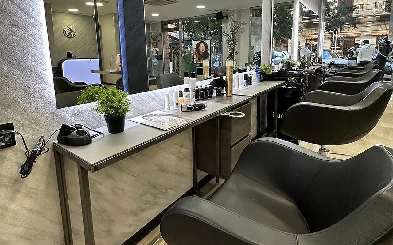 The styling area of Equipe Beauty, with a row of black chairs along a marble-effect counter, a large backlit mirror, styling products and a potted plant on the counter, and floor-to-ceiling windows looking onto the street.