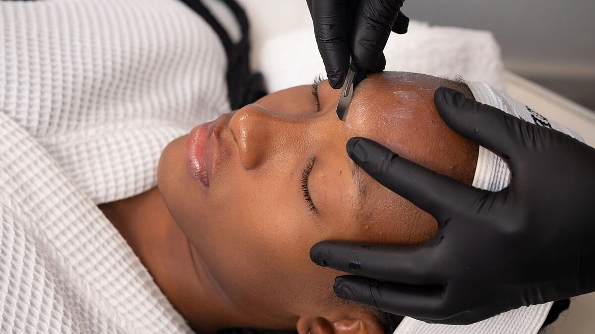 Close-up of an aesthetician performing dermaplaning on a client in salon