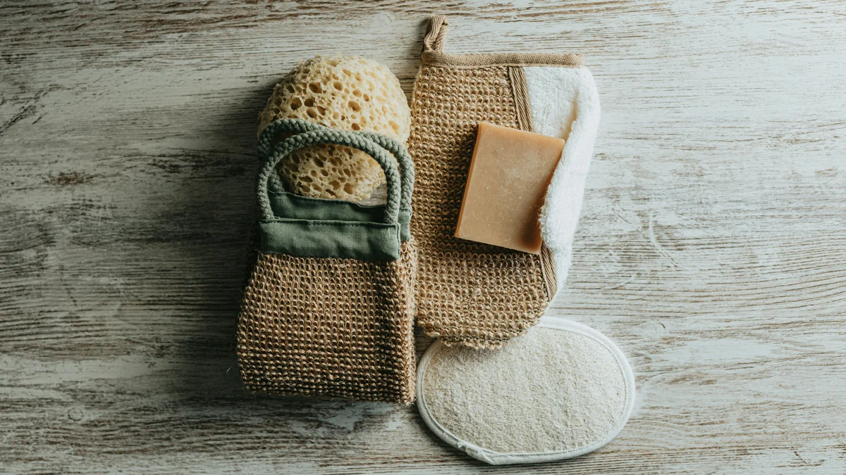 Flay lay of exfoliating mitts, a natural sponge, and an exfoliating soap