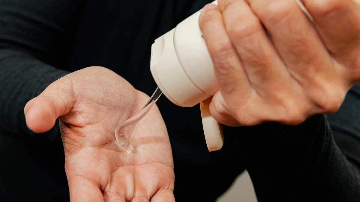 Close-up of a man’s hands as he uses one hand to squeeze a white tube of moisturising gel into his other hand